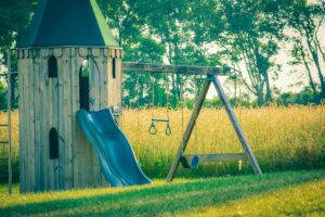 Timber tower with sway and chute near meadow with trees and lush verdant grass
